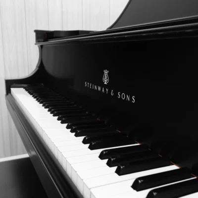 A 1911 Steinway A piano in a beautiful hand-rubbed satin ebony finish with nickel hardware. This image shows off the interior of the piano, including the harp and strings. This image shows off the keys and Steinway Logo on the fallboard.