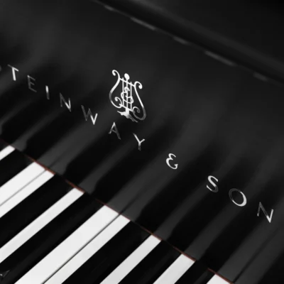 A 1911 Steinway A piano in a beautiful hand-rubbed satin ebony finish with nickel hardware. This image shows off the interior of the piano, including the harp and strings. This image shows off the keys and Steinway Logo on the fallboard.