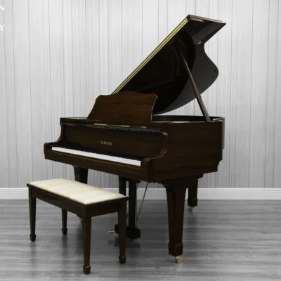 A Yamaha G1 piano in a beautiful mahogany finish with brass hardware and a bench.