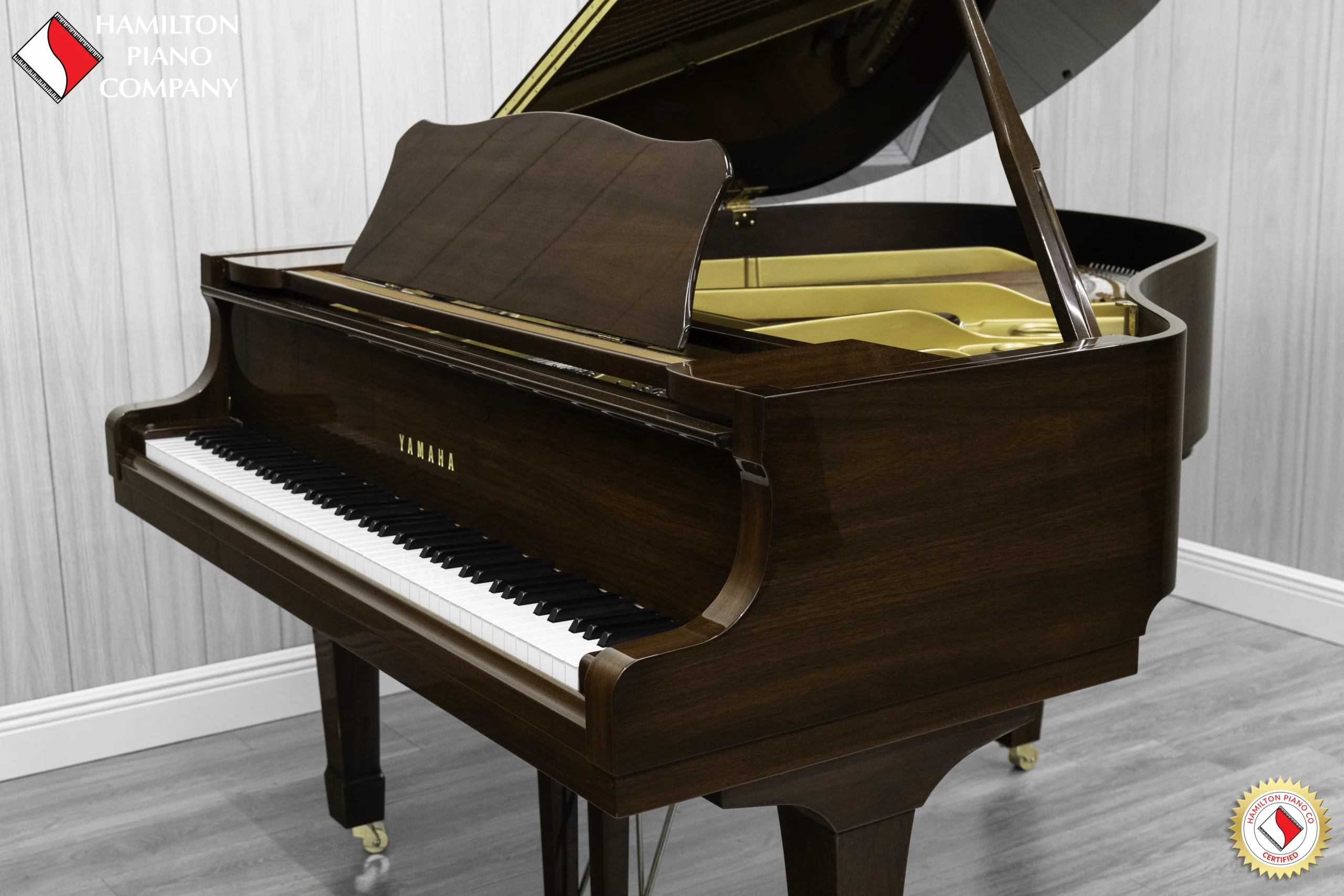 A Yamaha G1 piano in a beautiful mahogany finish with brass hardware.