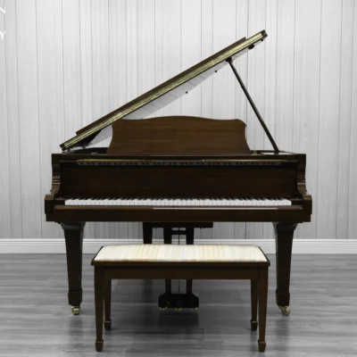A Yamaha G1 piano in a beautiful mahogany finish with brass hardware and a bench.