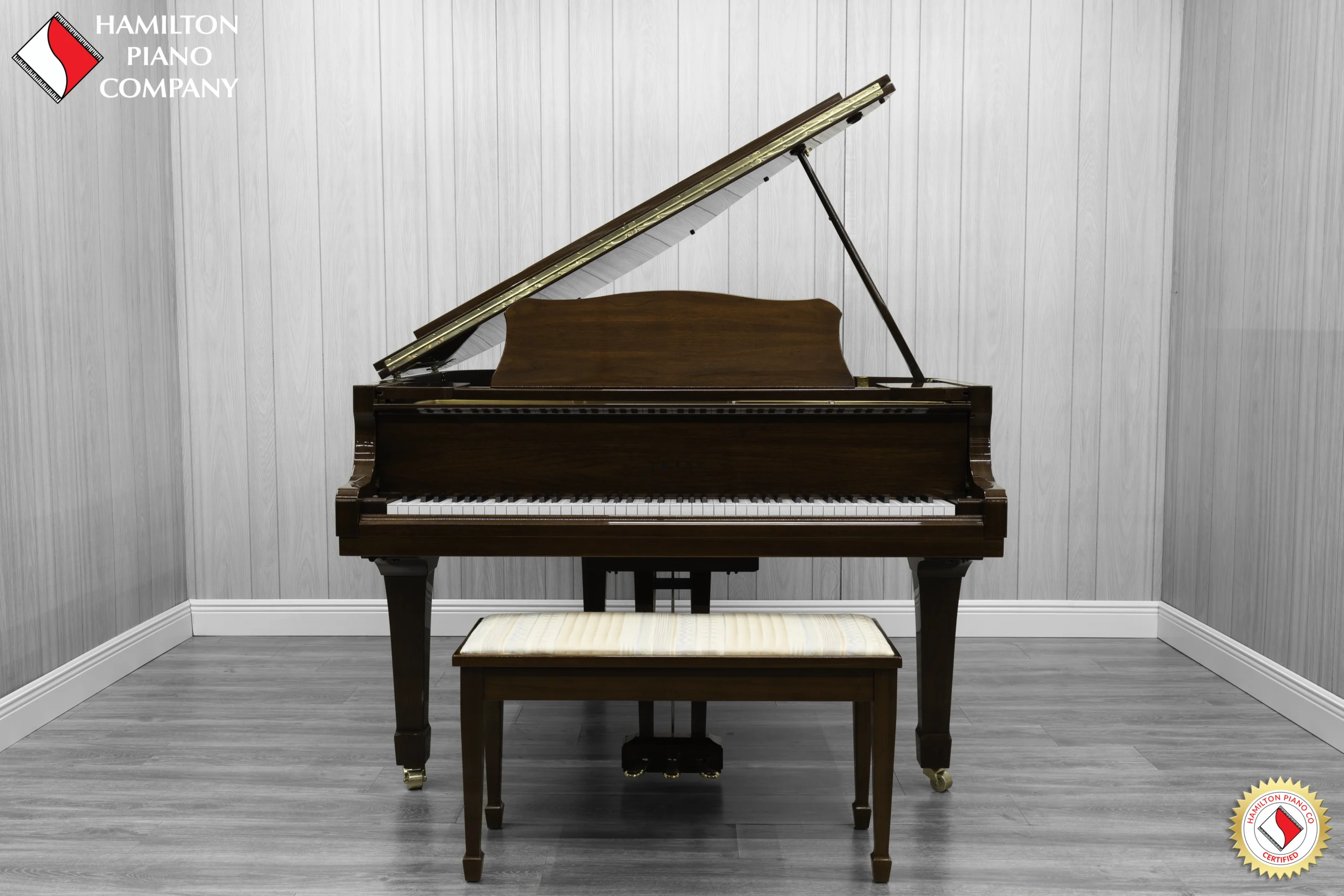 A Yamaha G1 piano in a beautiful mahogany finish with brass hardware and a bench.