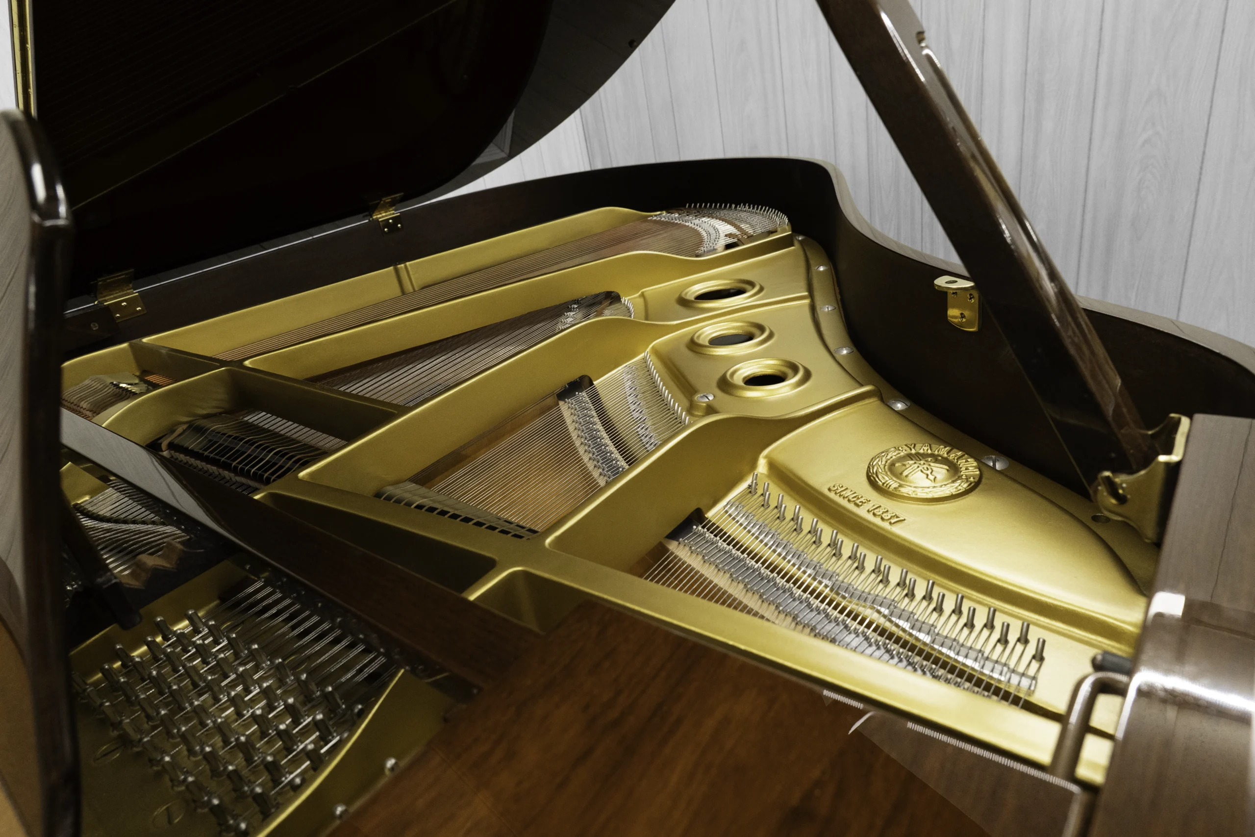 A Yamaha G1 piano in a beautiful mahogany finish with brass hardware. This image shows off the interior of the piano including the harp and strings.