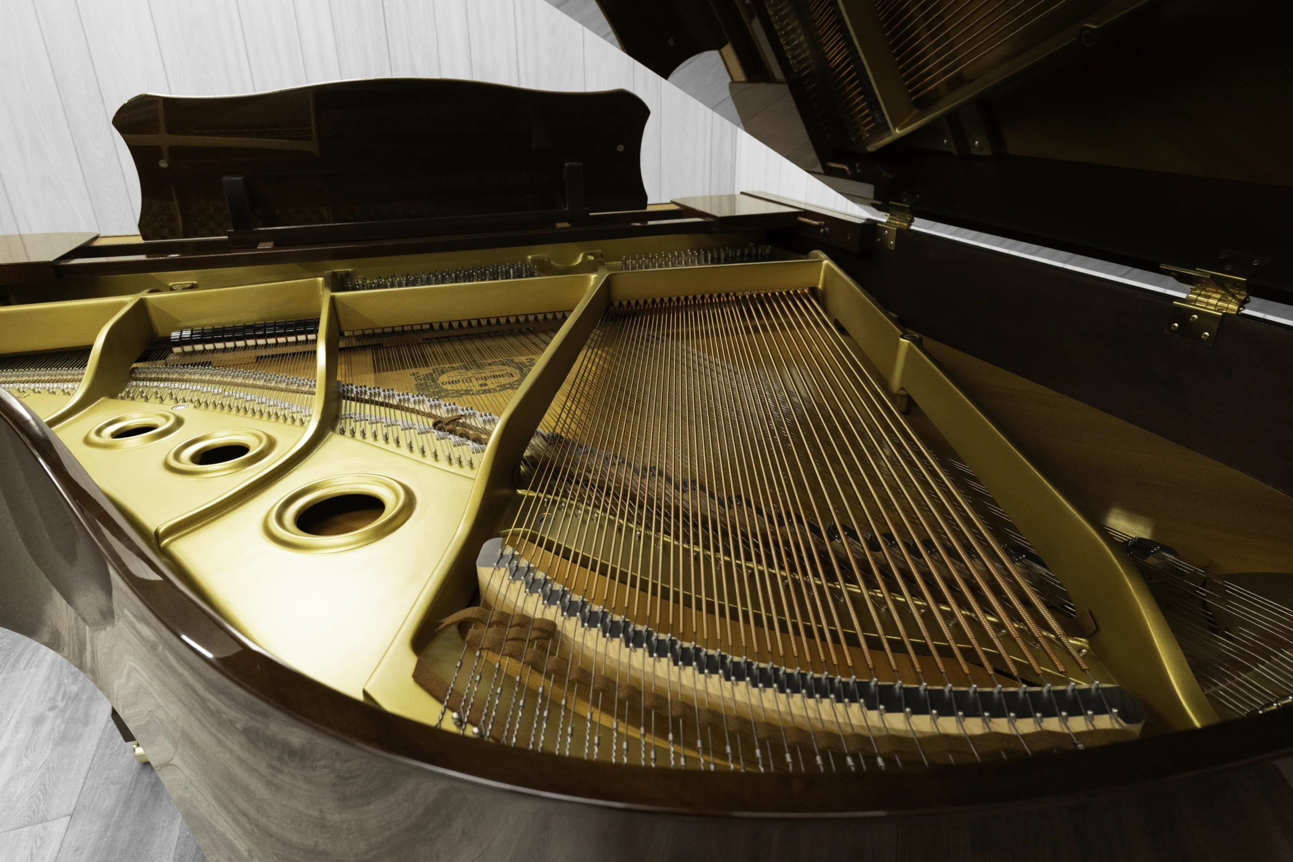 A Yamaha G1 piano in a beautiful mahogany finish with brass hardware. This image shows off the interior of the piano including the harp and strings.