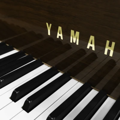 A Yamaha G1 piano in a beautiful mahogany finish with brass hardware. This image shows off the keys and fallboard logo.