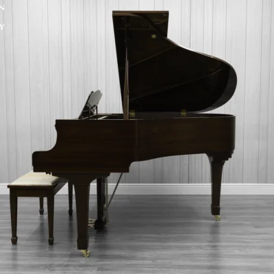 A Yamaha G1 piano in a beautiful mahogany finish with brass hardware and a bench.