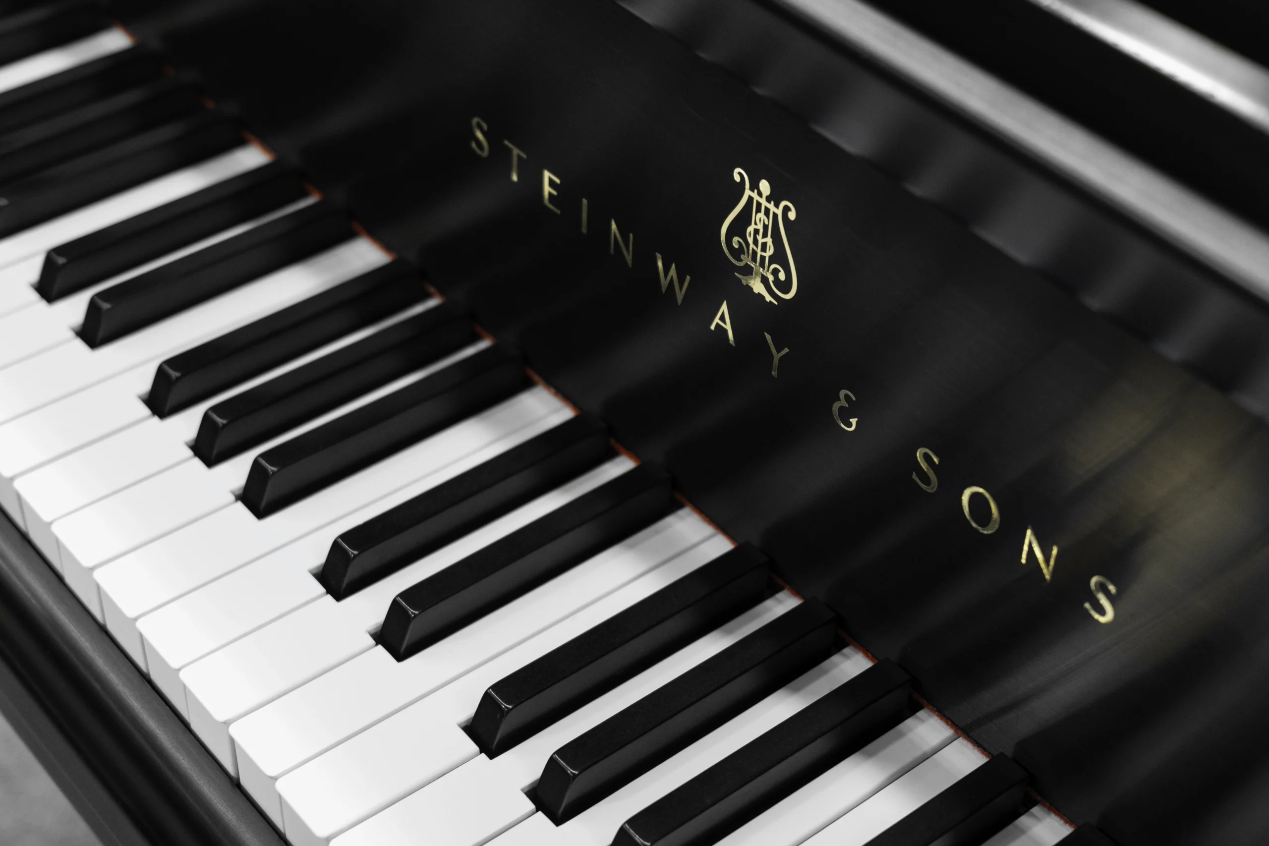 a close up on the keys and logo of a Steinway D concert grand piano in a hand-rubbed satin ebony finish.